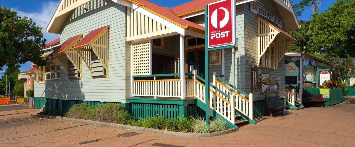 A heritage post office building with a red roof and green trim.
