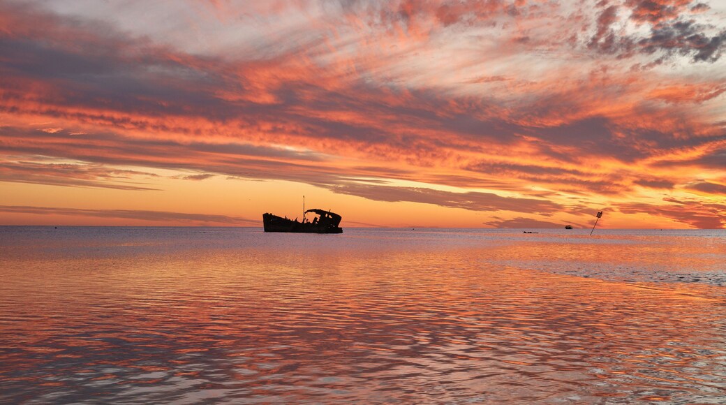 View of a red and orange fiery sunset reflected in The Ocean at Heron Island with a shipwreck in the distance, Great Barrier reef, Queensland, Australia