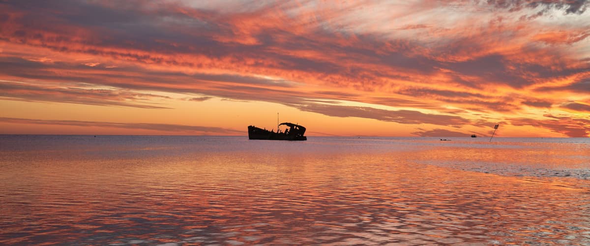 A boat on calm water during sunset with a vibrant sky.