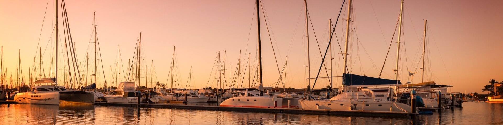 A marina with multiple sailboats docked at sunset.