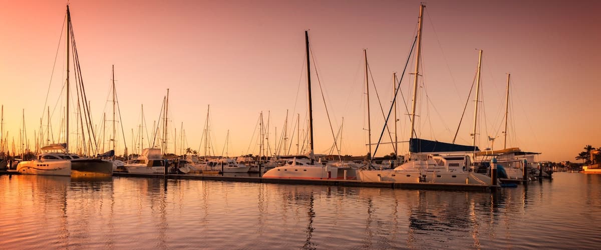 A marina with multiple sailboats docked at sunset.