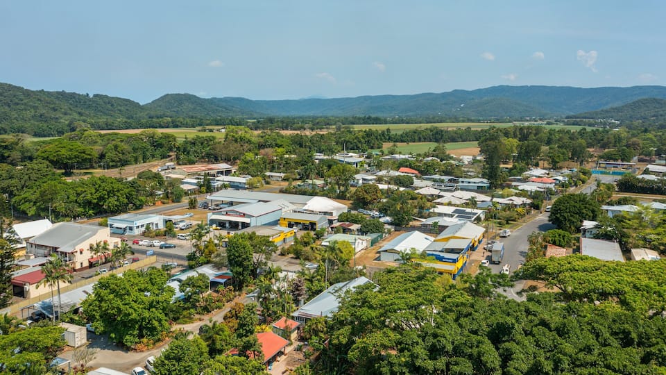 A town with buildings, roads, and green hills in the background.