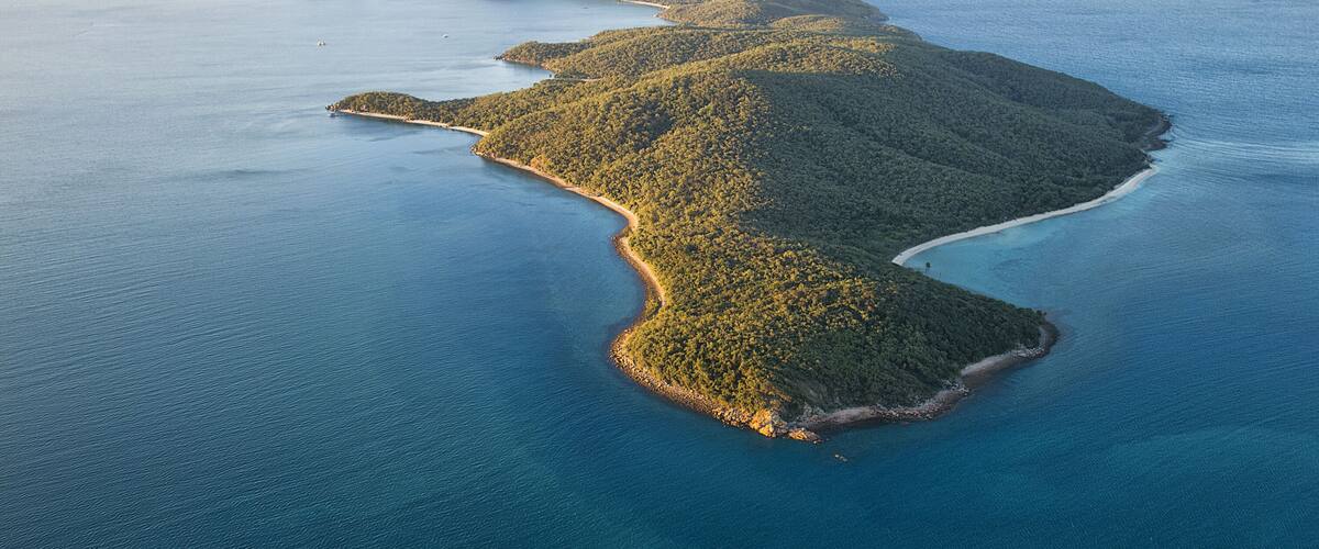 An aerial view of a series of islands with dense forests and clear blue waters.