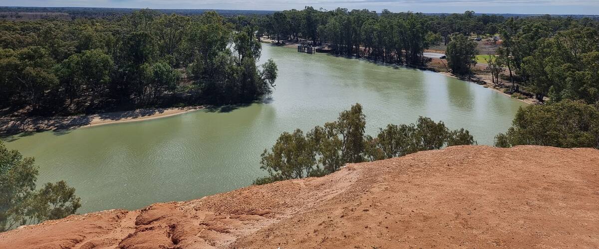 A river winding through a forested area with a clear sky.