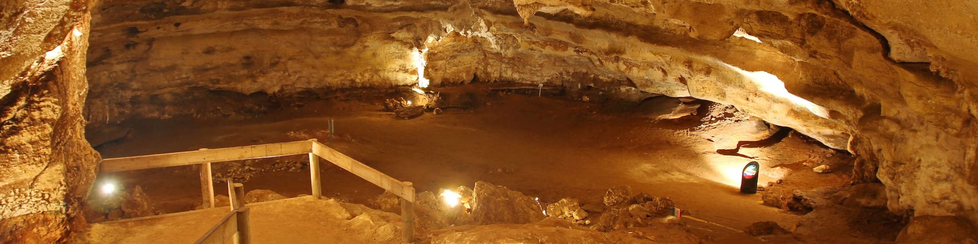 A cave with a wooden walkway and a small pool of water.