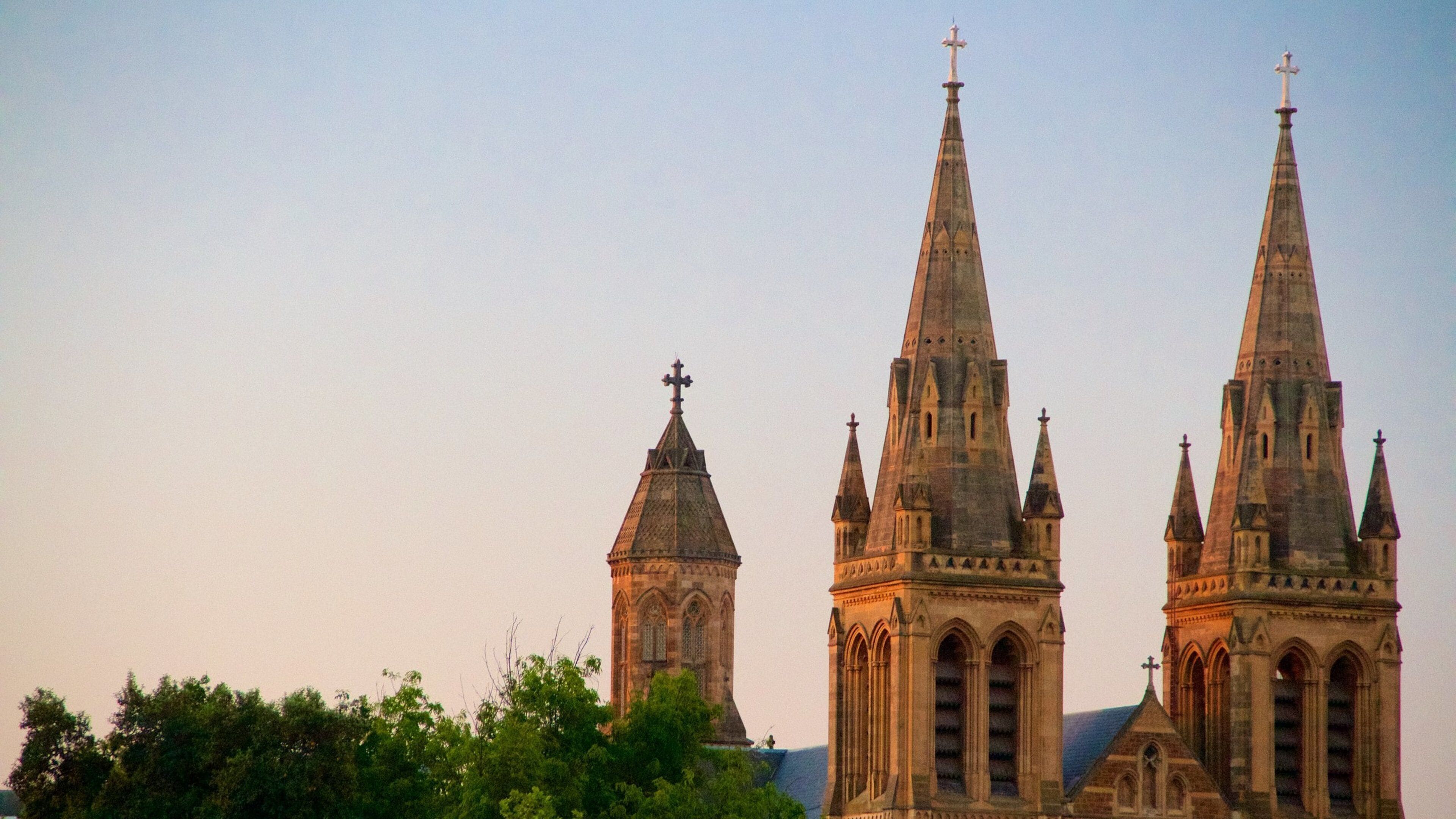 Een historisch kerkgebouw met meerdere spitsen en kruisen.
