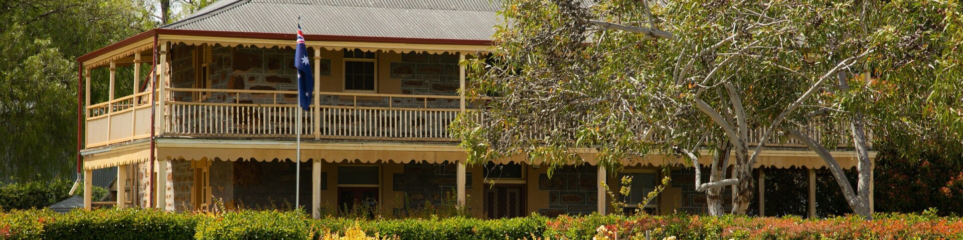 A large, two-story building with a balcony, surrounded by well-maintained gardens and trees.