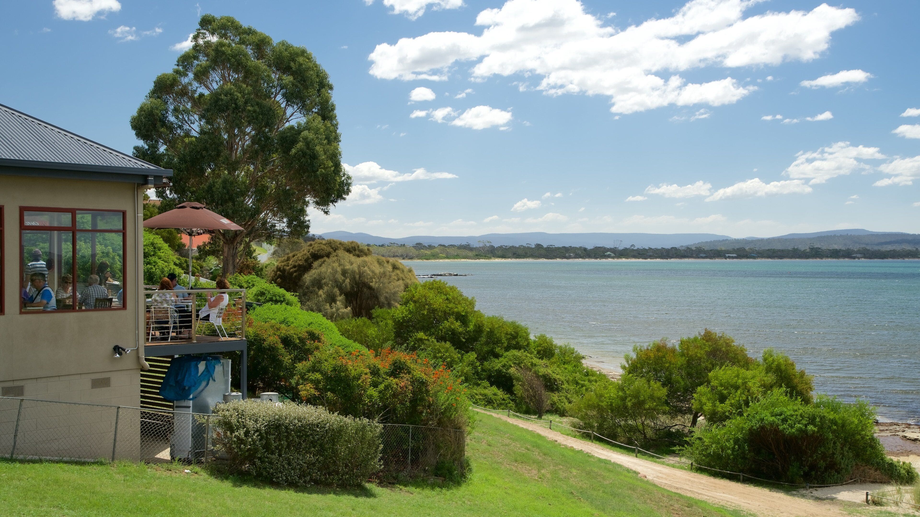 A lakeside view with a building, trees, and a clear sky.