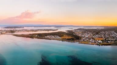 Vista aérea de uma vila costeira com uma grande baía, rodeada por florestas e ilhas.