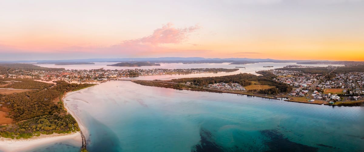 An aerial view of a coastal town with a large bay, surrounded by forests and islands.