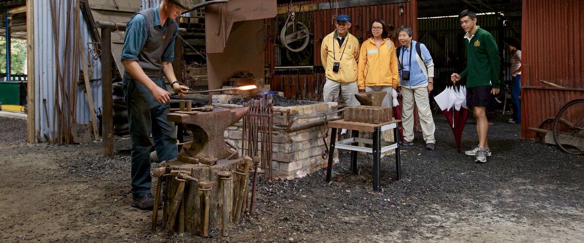 A blacksmith at work with a group of onlookers.