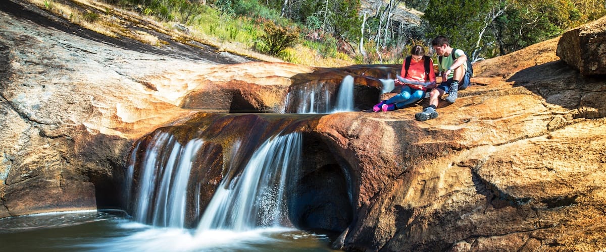 A waterfall cascading over a rocky outcrop surrounded by trees.
