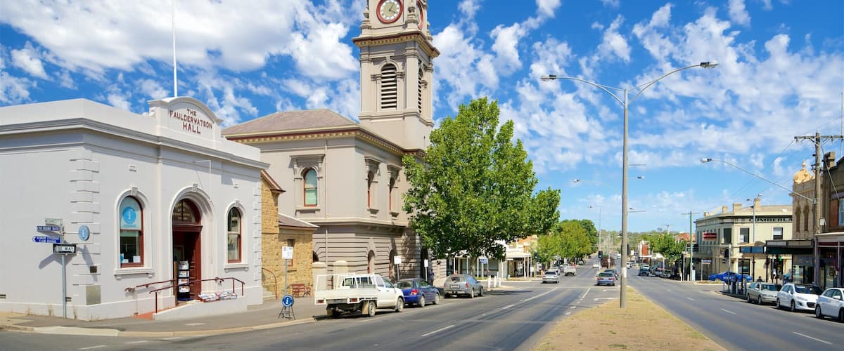 A street with a clock tower, a sign for The Faulderwatson Hall, and a clear blue sky.