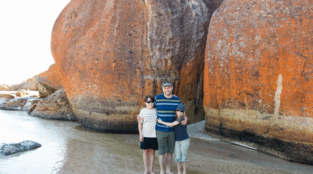 a father, daughter and son wearing sun glasses and a hat next to boulder rocks at Squeaky beach in Wilson's Promontory South Gippsland Australia