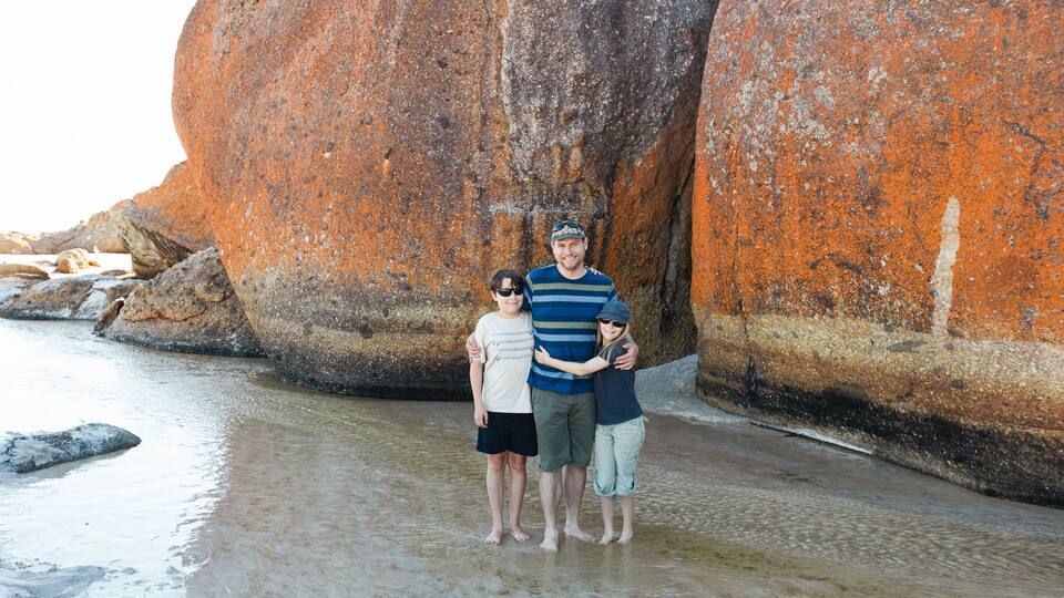 a father, daughter and son wearing sun glasses and a hat next to boulder rocks at Squeaky beach in Wilson's Promontory South Gippsland Australia