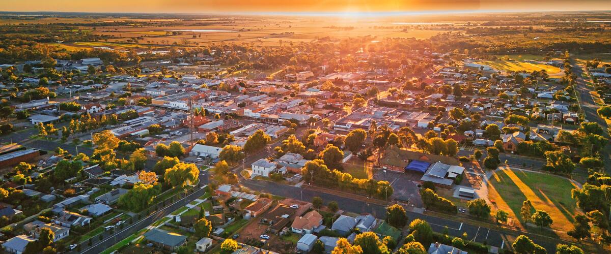 An aerial view of a town during sunset with a visible river and surrounding fields.