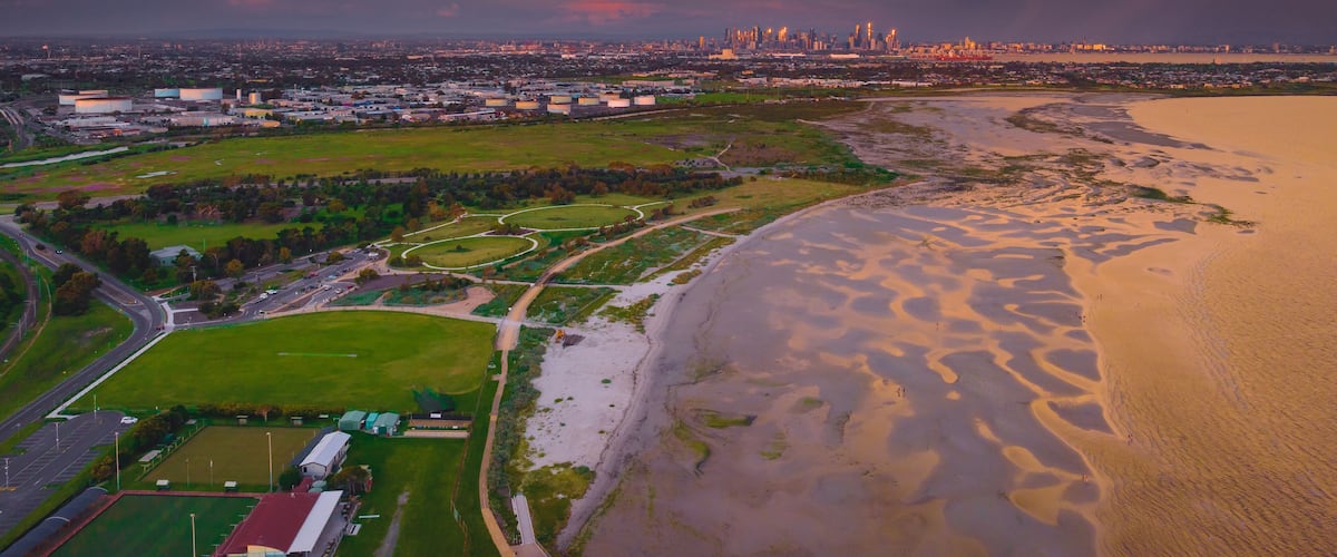 Aerial view of a dramatic storm cloud over a bayside beach and coastal parkland