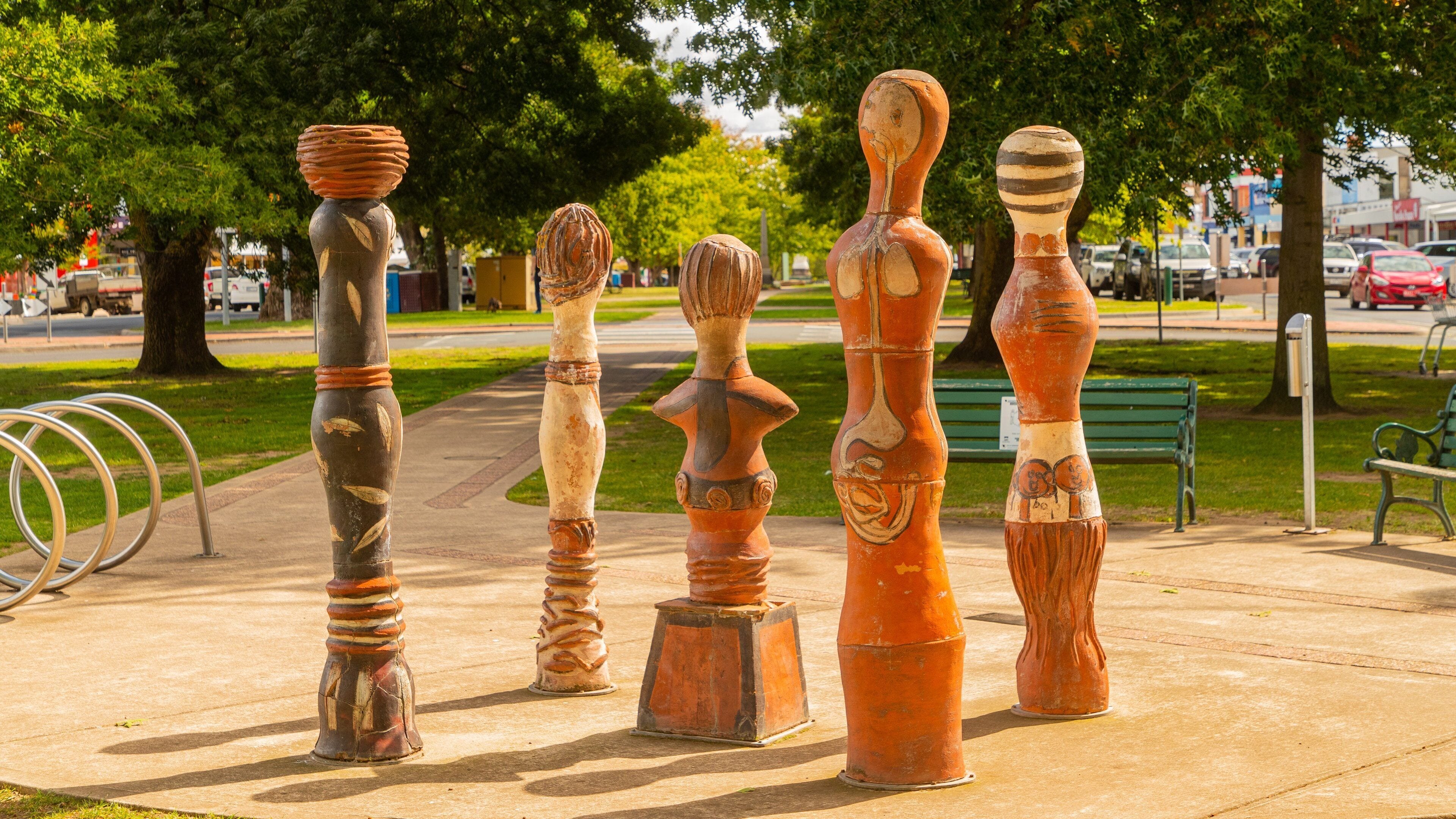 Una fila de piezas de arte escultórico únicas en una acera de un parque.