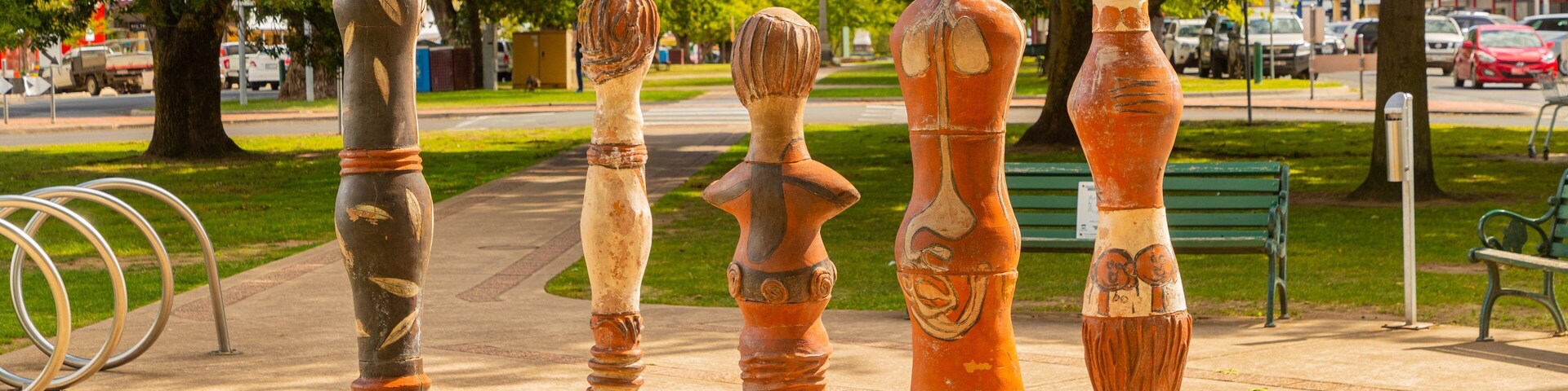 Una fila de piezas de arte escultórico únicas en una acera de un parque.