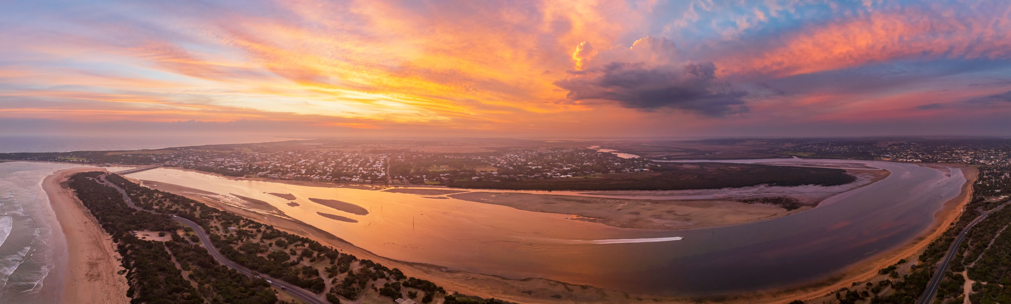 A coastal landscape with a winding river, a beach, and a city in the distance.