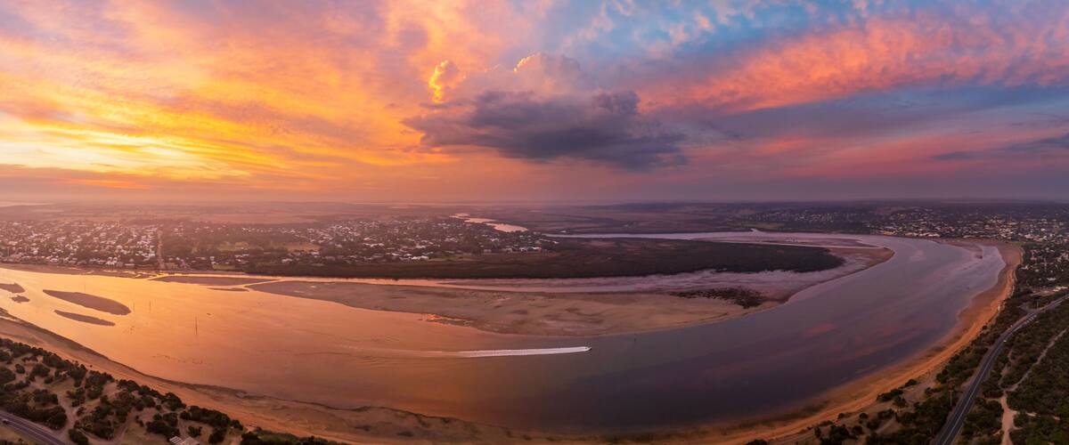 A coastal landscape with a winding river, a beach, and a city in the distance.