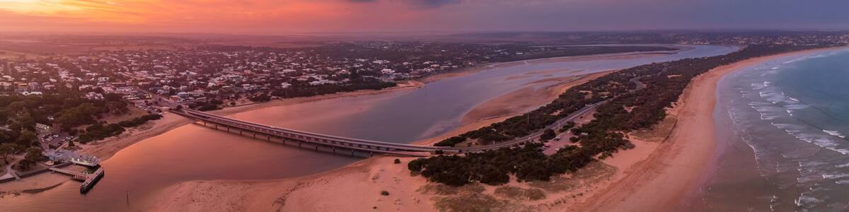 A coastal landscape with a bridge, beach, and a river.