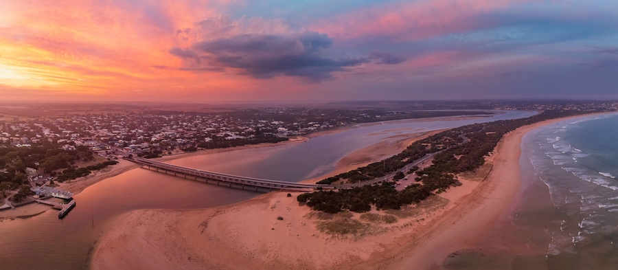 A coastal landscape with a bridge, beach, and a river.
