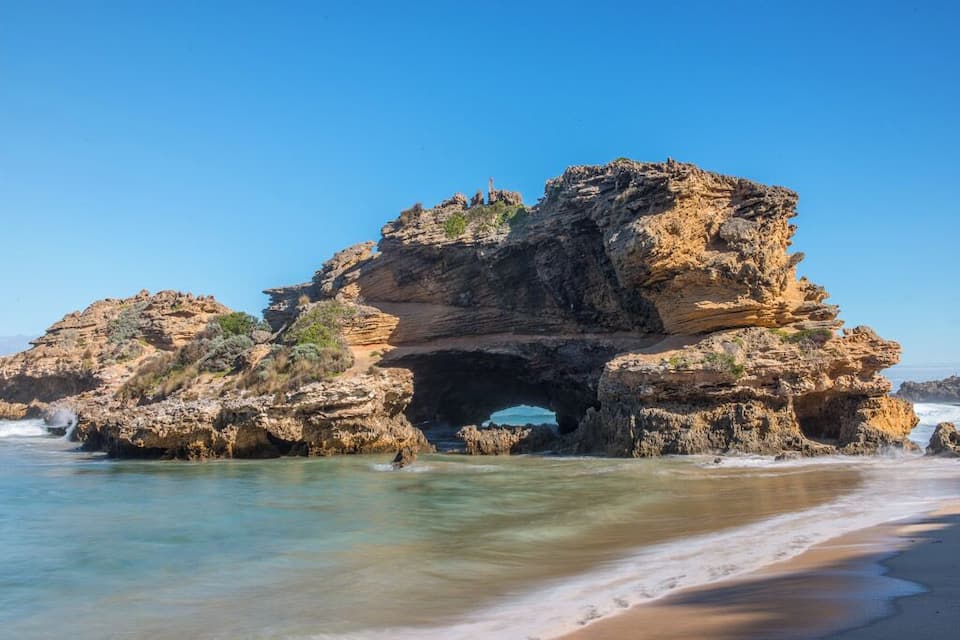 A large rock formation with a natural arch over the ocean.