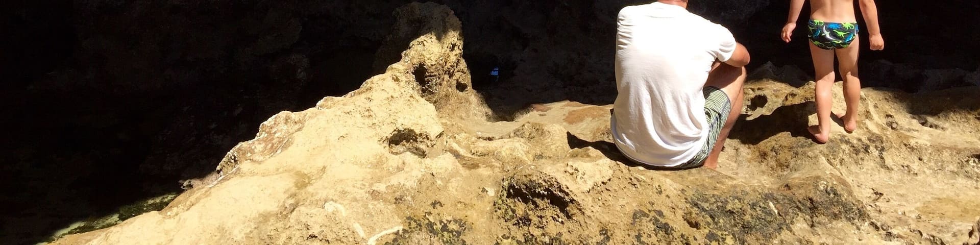 A cave opening to a beach with waves crashing against rocks.