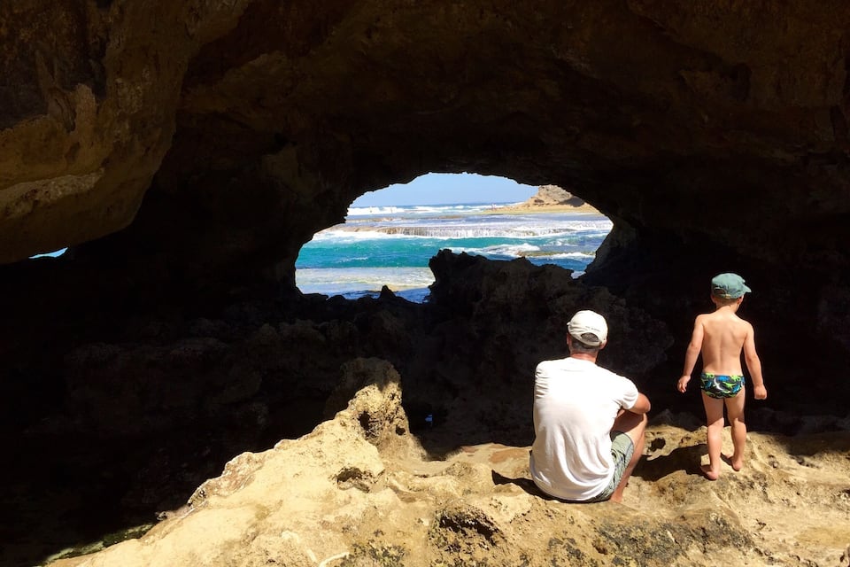 A cave opening to a beach with waves crashing against rocks.