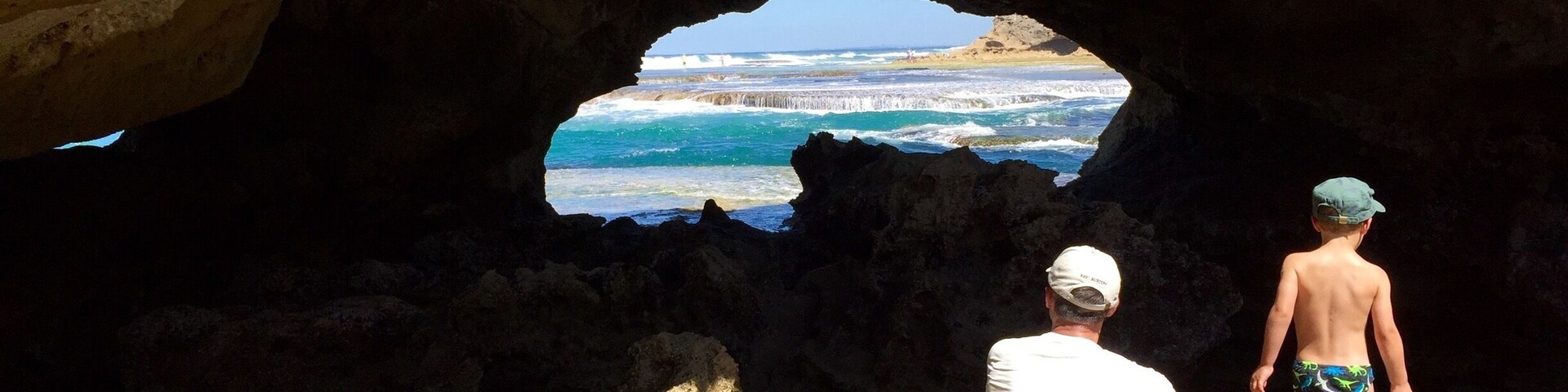 Una cueva que se abre a una playa, con olas rompiendo contra las rocas.