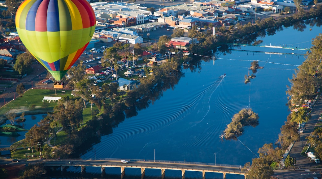 A hot air balloon over a river with a bridge and a town.