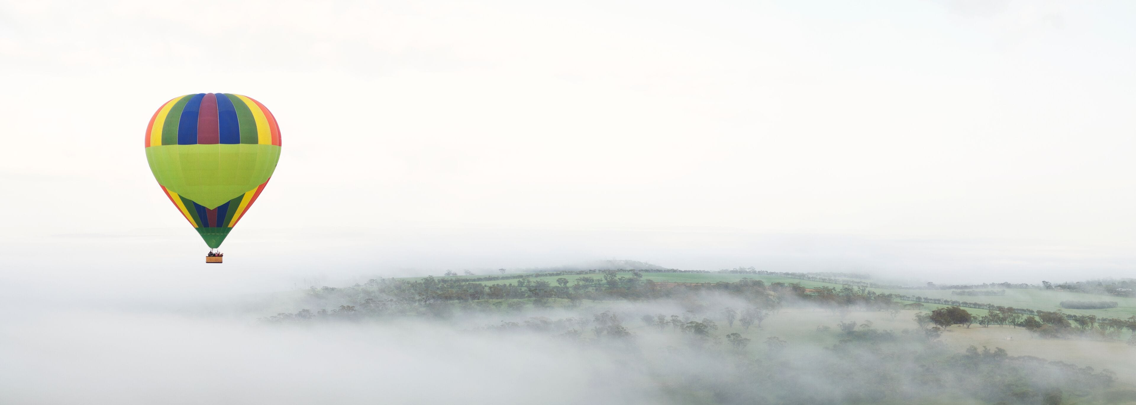 Hot Air Ballooning Above Foggy Hills