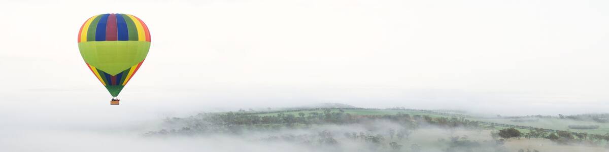 Hot Air Ballooning Above Foggy Hills