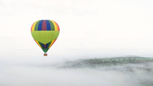 Hot Air Ballooning Above Foggy Hills