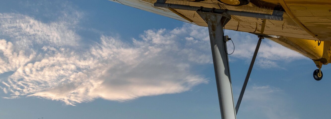 Un avión amarillo exhibido, un monumento de piedra y una placa.