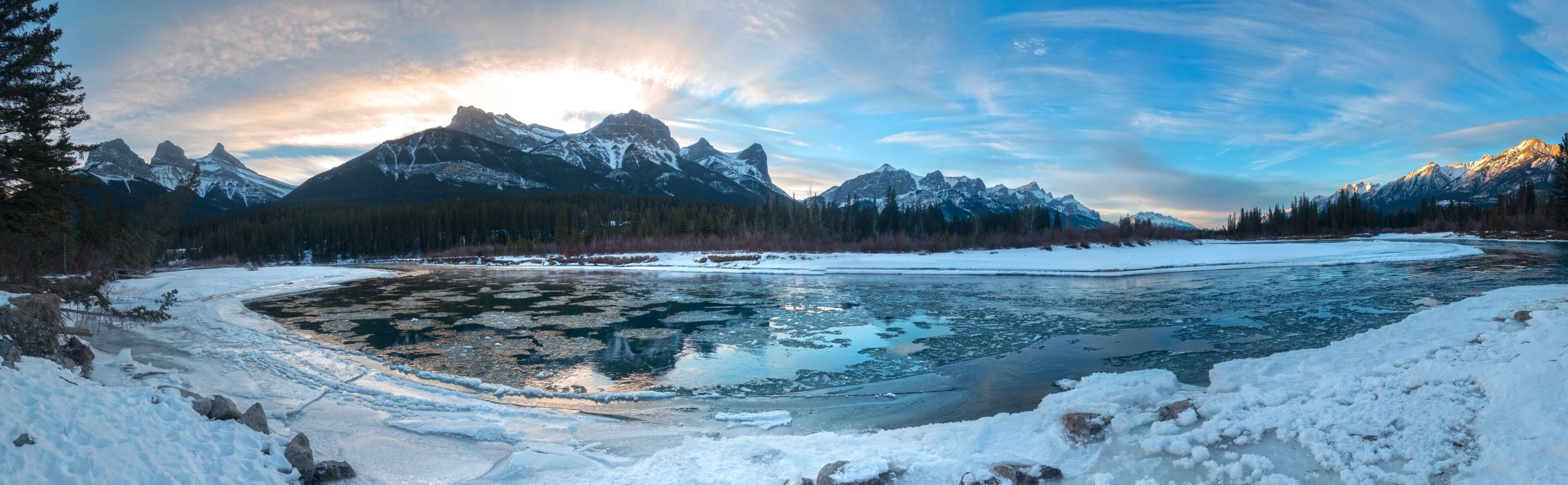 Wide Panoramic Landscape of Bow River and Mountain Peaks on a cold winter day near Canmore, Alberta in Canadian Rockies