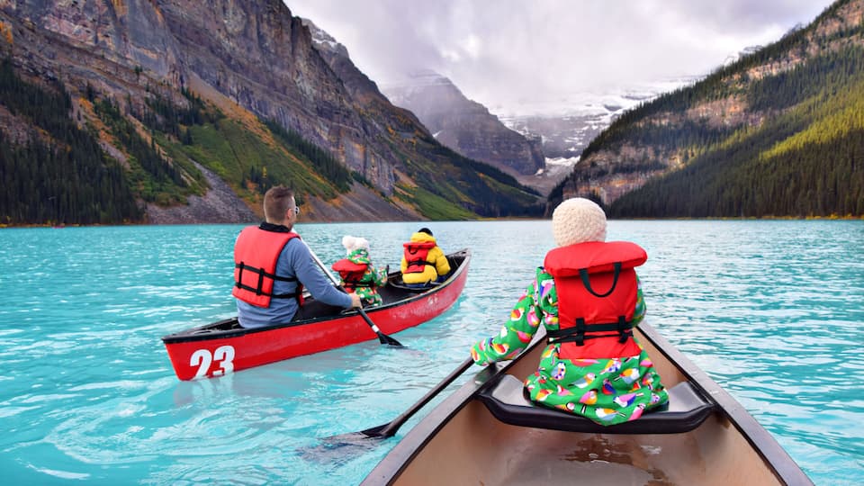 A calm lake with a red canoe marked '23' and two people wearing life jackets.
