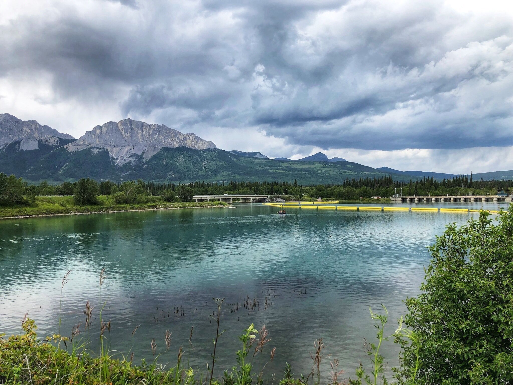 A lake with mountains in the background and a bridge over the water.