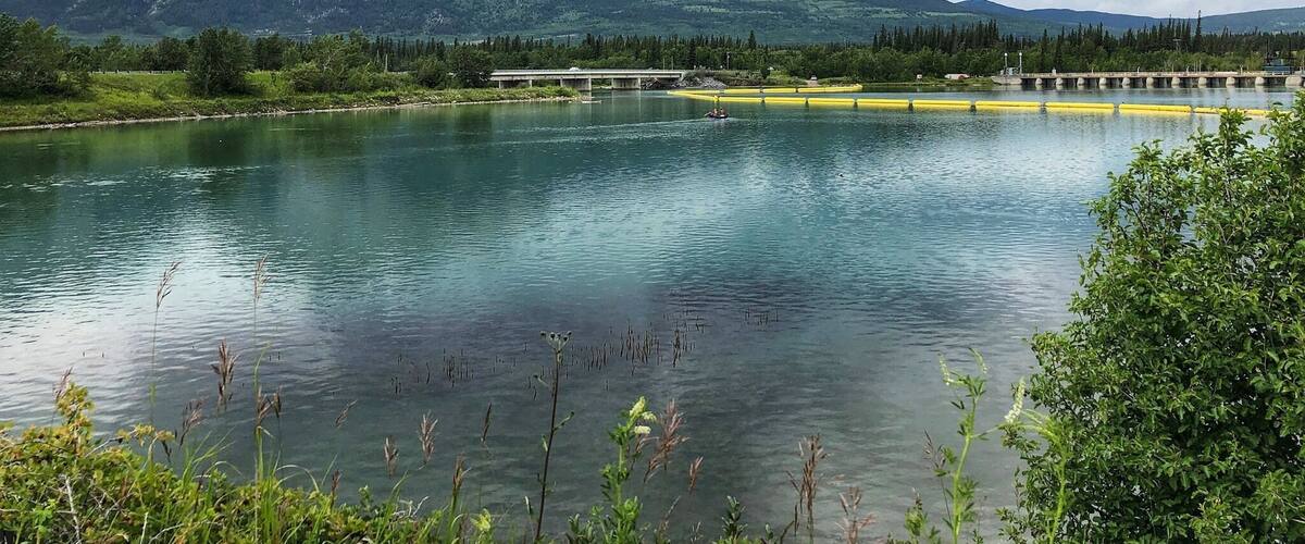A lake with mountains in the background and a bridge over the water.