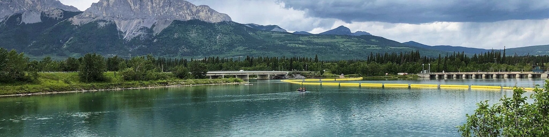 A lake with mountains in the background and a bridge over the water.