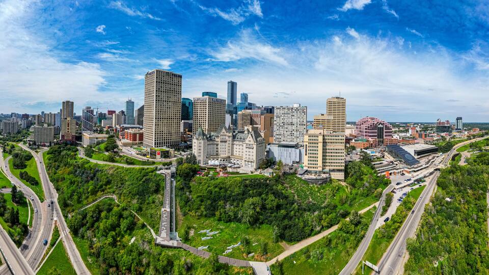 A city skyline with high-rise buildings, a river, and a park with winding roads.