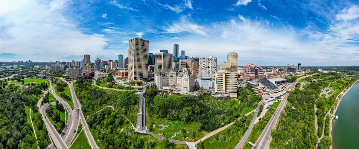 A city skyline with high-rise buildings, a river, and a park with winding roads.