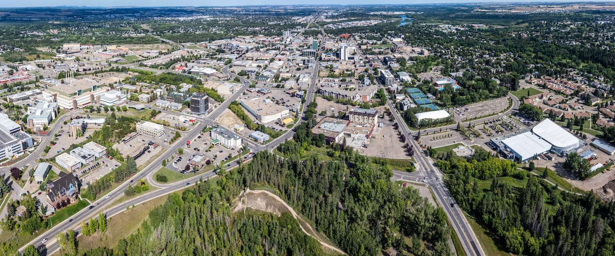 An aerial view of a town with a mix of commercial buildings, roads, and green spaces.