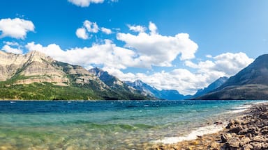 A mountain range, clear blue lake, and rocky shoreline.