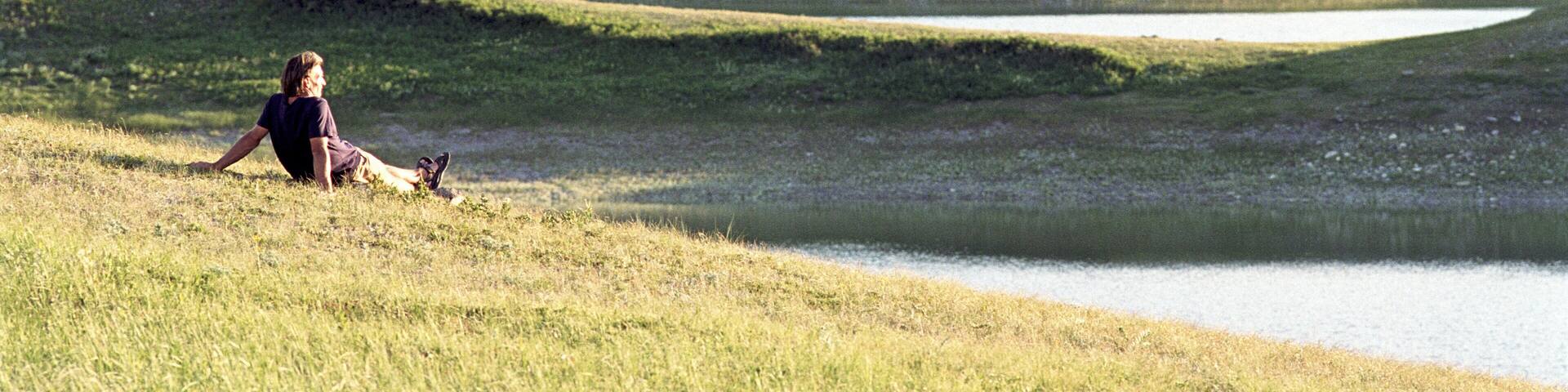 Canada, Alberta, Waterton Lakes, man sitting on grass, rear view