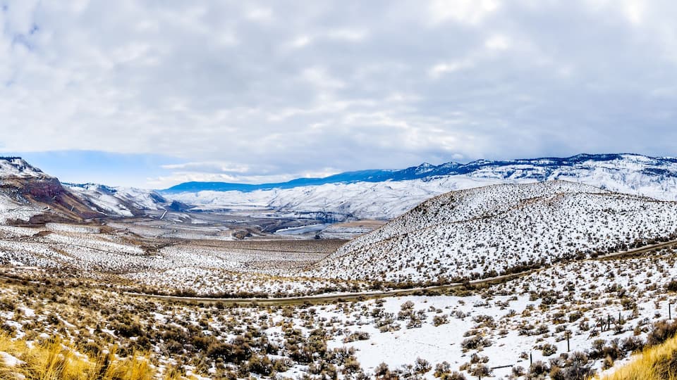 A snow-covered mountainous landscape with a winding road.