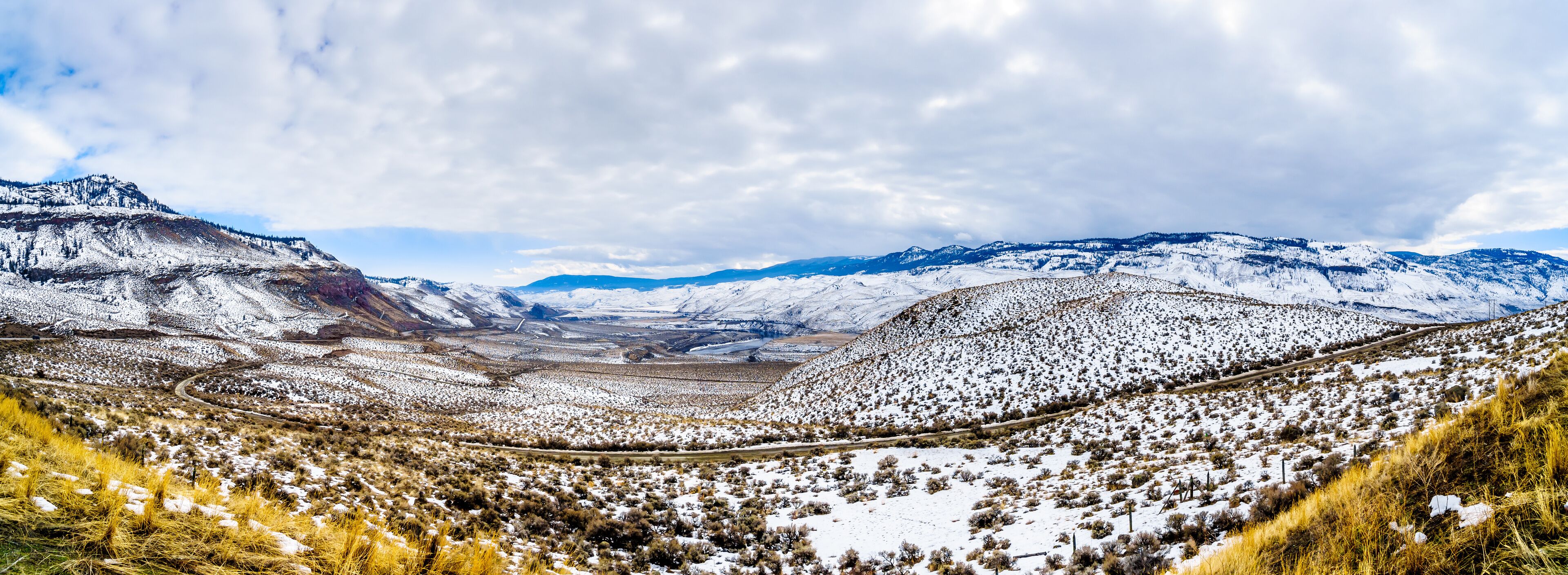 A snow-covered mountainous landscape with a winding road.