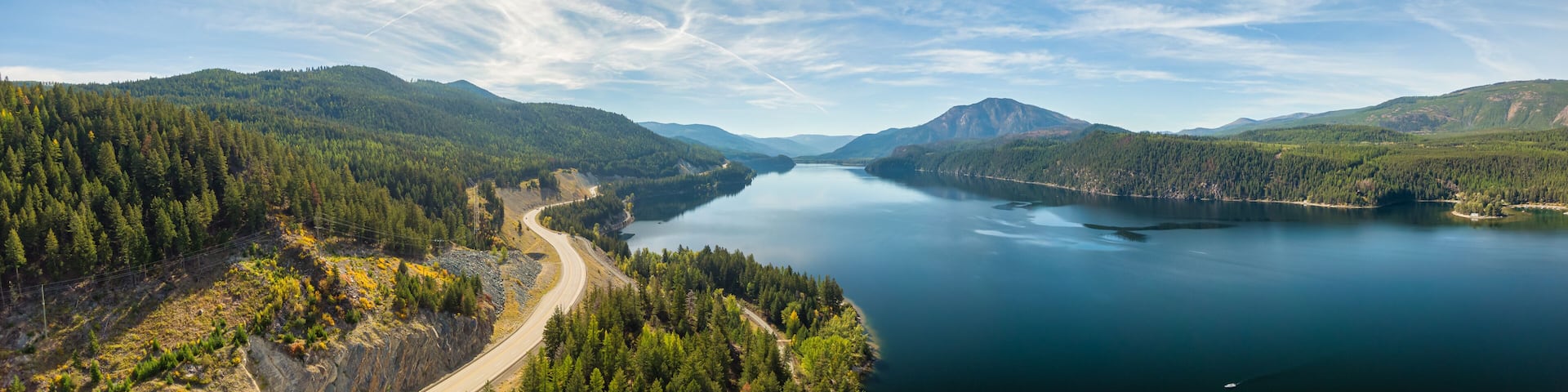 Aerial panoramic view of a scenic highway around mountains. East Kootenay, British Columbia, Canada.