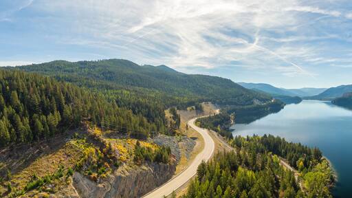 Aerial panoramic view of a scenic highway around mountains. East Kootenay, British Columbia, Canada.